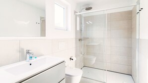 Une salle de bain moderne avec une douche à parois de verre, un lavabo blanc et des toilettes.