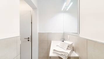 A modern bathroom with a white sink, a mirror, and a towel rack.