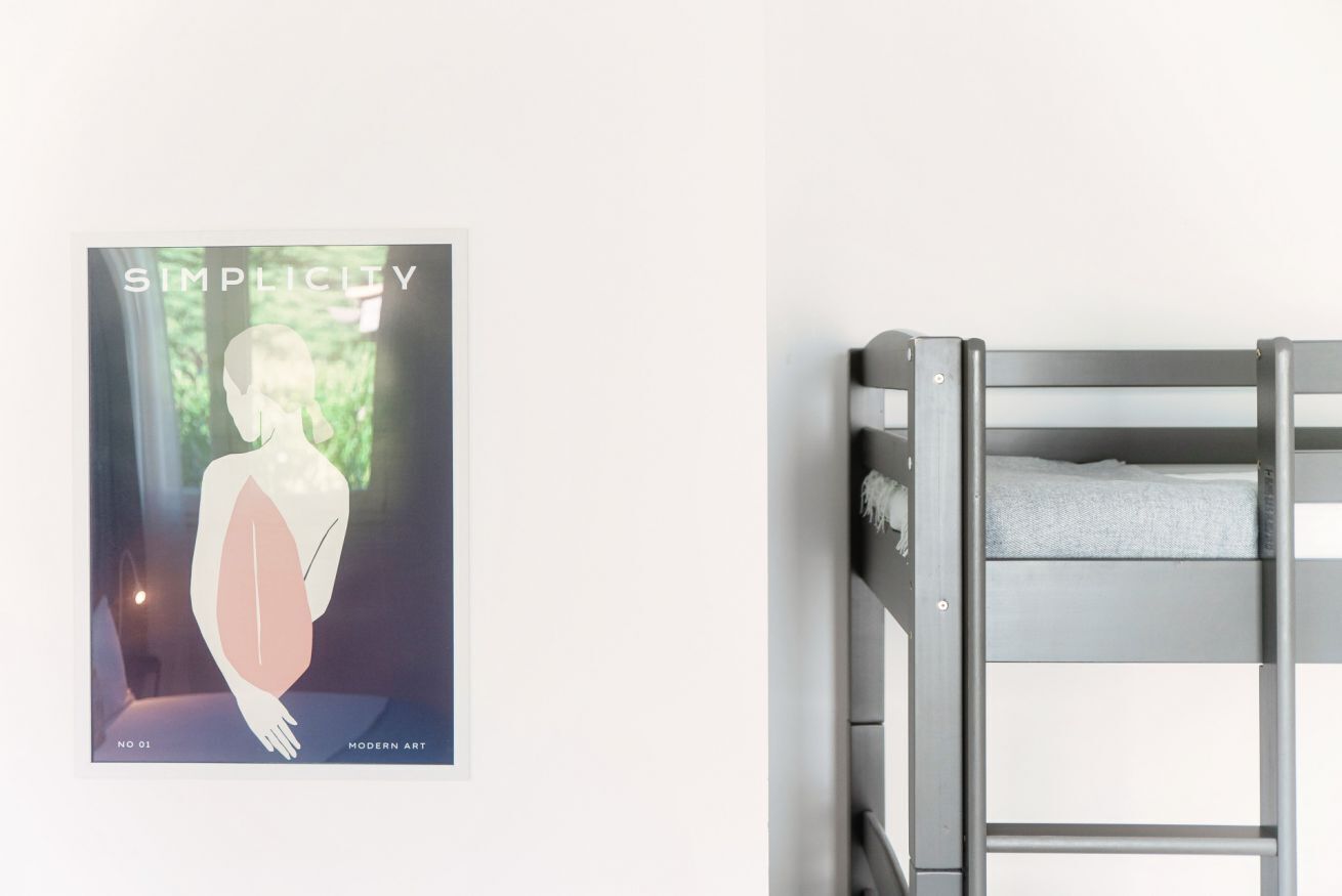 Un lit superposé avec un matelas blanc et un luminaire fixé au mur.
