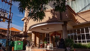 A building with a curved entrance, potted plants, and a green generator outside. - Puri Dibia Hotel (Kuta)