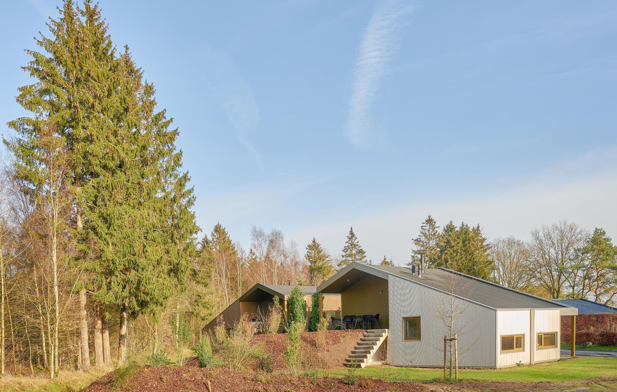 A modern house with a sloped roof, a covered outdoor area, and a staircase leading to a deck.