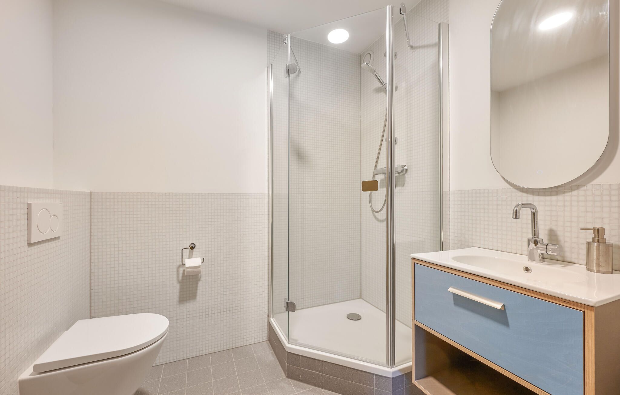Ein modernes Badezimmer mit einer Duschkabine, einer Toilette und einem Waschtisch mit Spiegel.