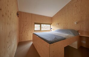Cozy retreat with a sloped ceiling, wooden paneling, and a comfortable bed.