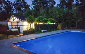 Enjoy a refreshing swim in the pool surrounded by a lush lawn and trees.