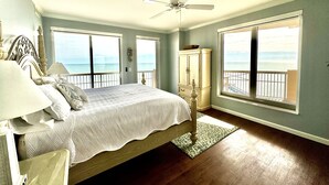 Una camera da letto con un letto, un comodino, una cassettiera e una ventola a soffitto. Sono presenti due finestre con vista sull'oceano.