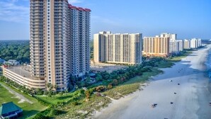 Un hotel moderno con tetto rosso, vicino a una spiaggia con alcune persone.