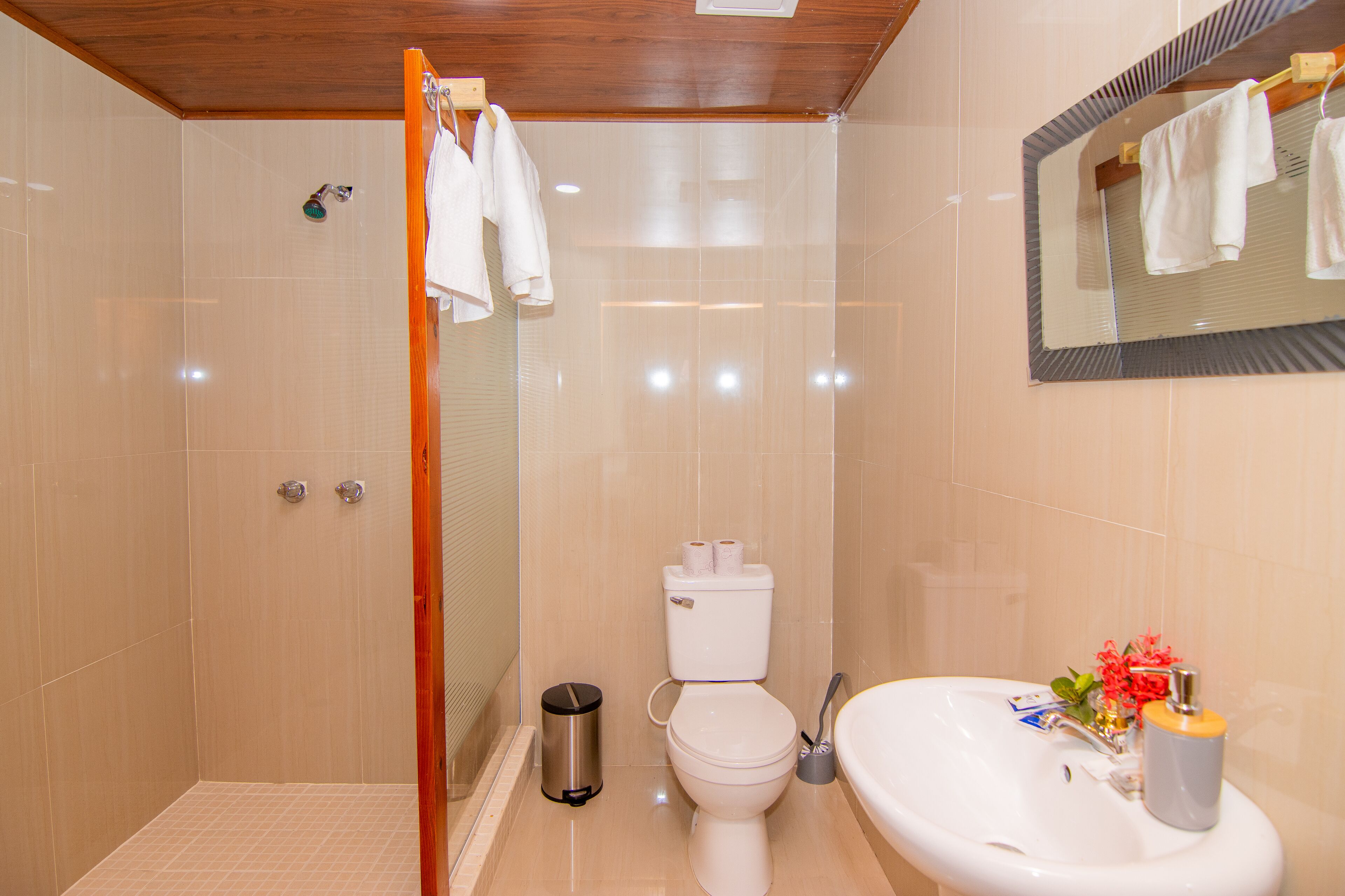 A bathroom with a shower, toilet, sink, and a mirror.