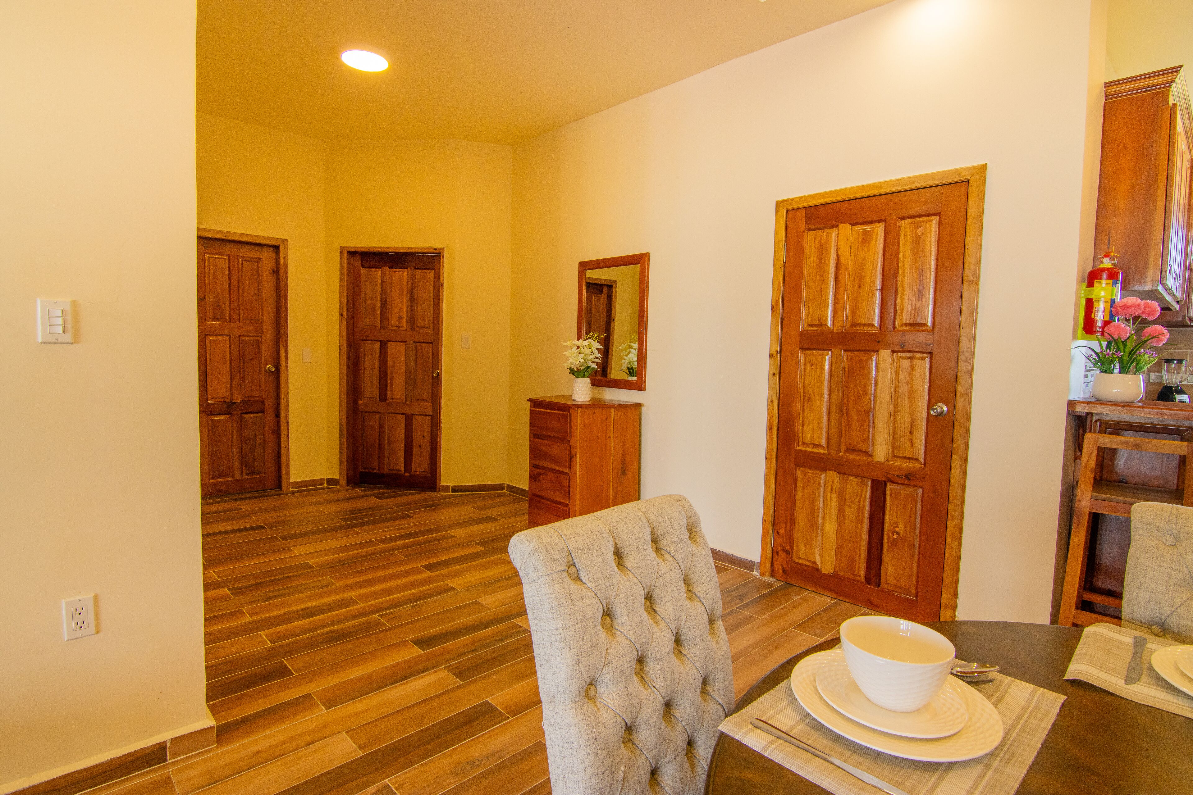A dining area with wooden flooring, a table set with plates, a bowl, and cutlery.