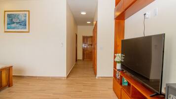 A hallway with a wooden entertainment unit, a television, and a framed painting on the wall.