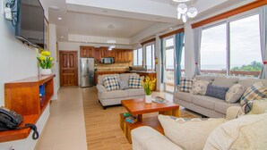 A spacious living area with a sofa, coffee table, and a TV mounted on the wall. - Tropical Palace Hotel (San Pedro)