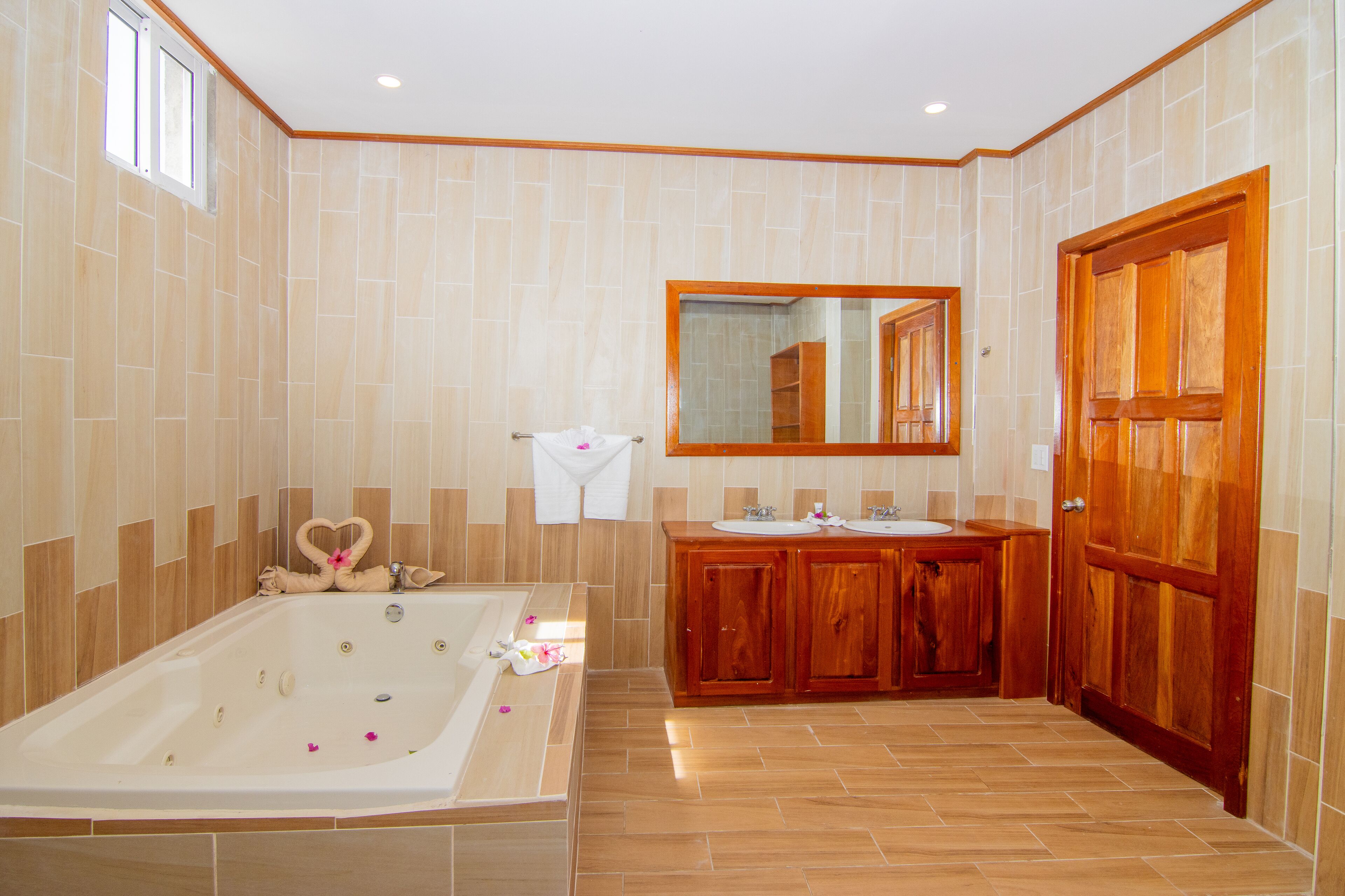 A spacious bathroom with a large bathtub, wooden cabinets, and a mirror above the sink.