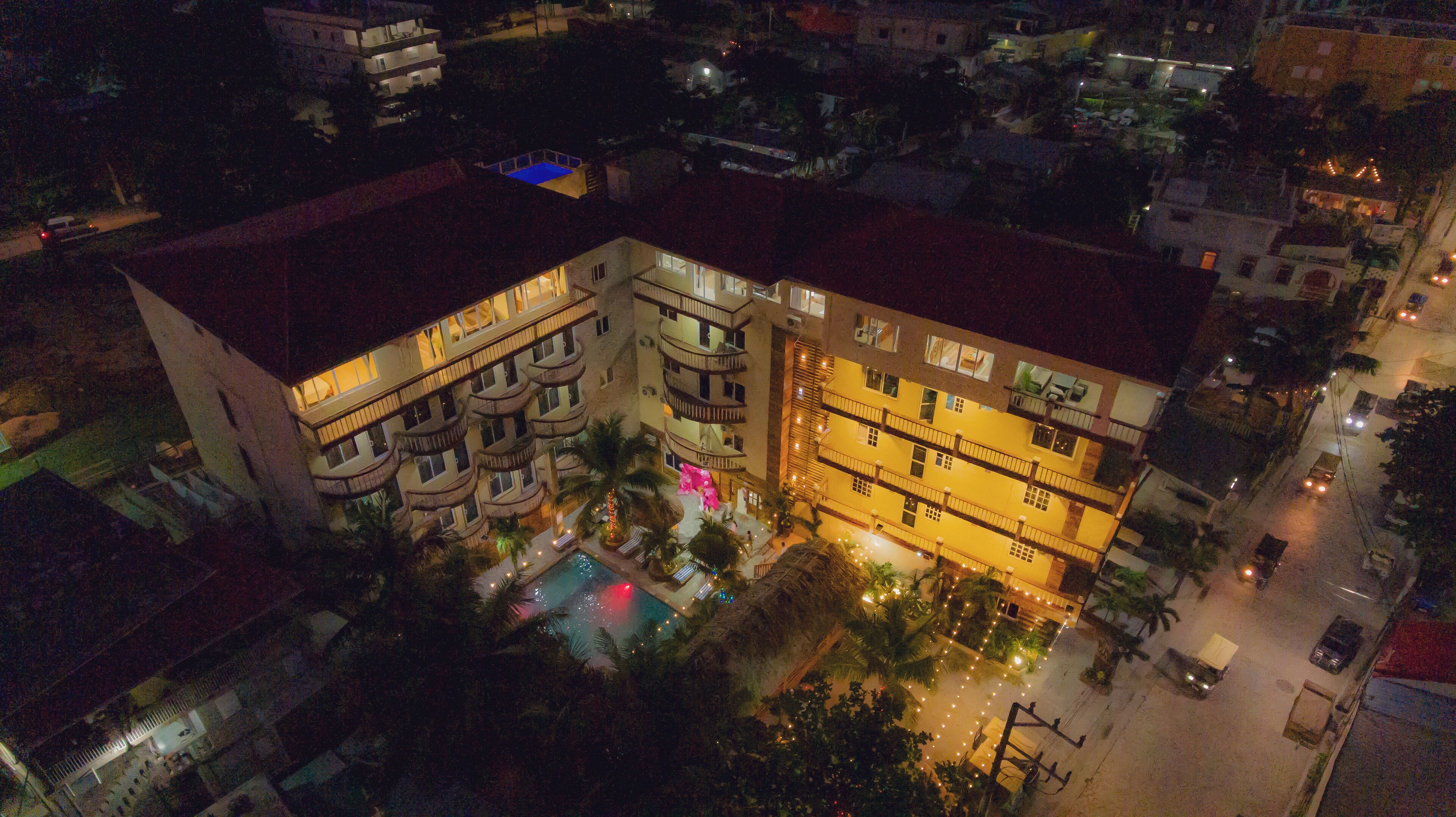 Un hotel de varios pisos con balcones, piscina y vista a la calle.