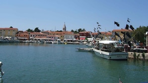 Un port où sont amarrés des bateaux, un clocher d’église imposant et des bâtiments aux couleurs vives qui bordent le front de mer.