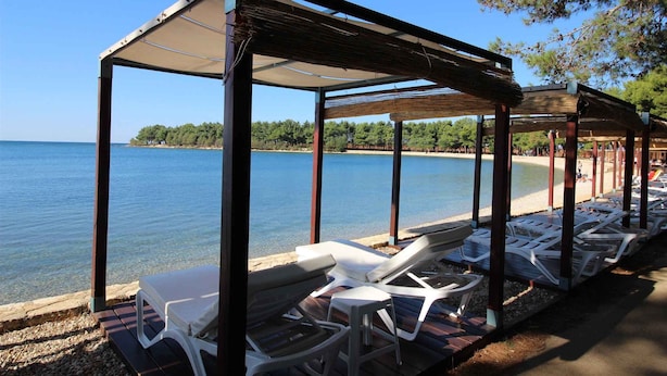 Un pavillon situé au bord de la plage, doté de chaises longues et offrant une vue sur la mer.