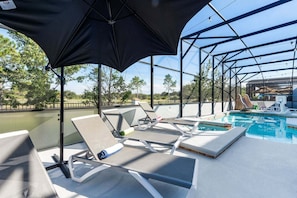A poolside area with lounge chairs, a pool, and a covered section with umbrellas.