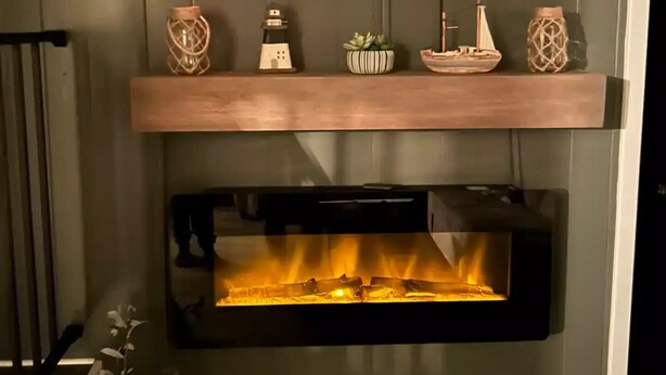 Moderni takka, jonka yläpuolella on televisio, hyllyt koriste-esineitä varten ja alla kasvi.