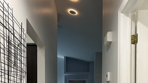 Un pasillo estrecho con suelo de madera, iluminación empotrada y una puerta a la derecha.
