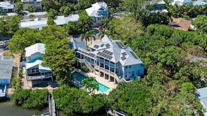 A coastal residential area with houses, a swimming pool, and a dock with a boat. - Serenity Cottage in Anna Maria (Anna Maria)