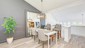 A modern dining area with a white table, beige chairs, and a hanging light fixture. - Perico Coastal Bay in Bradenton (Bradenton)