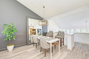 A modern dining area with a white table, beige chairs, and a hanging light fixture. - Perico Coastal Bay in Bradenton (Bradenton)