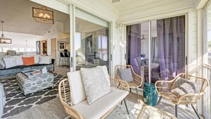 A spacious living area with a sofa, chairs, and a coffee table. There is a sliding glass door leading to an outdoor area. - Perico Coastal Bay in Bradenton (Bradenton)