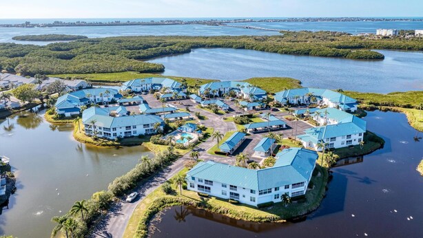 A coastal resort with multiple buildings featuring blue roofs, surrounded by water and greenery. - Perico Coastal Bay in Bradenton (Bradenton)