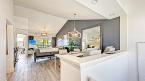 A modern living room with a dining area, a large mirror, and a view of the outdoors. - Perico Coastal Bay in Bradenton (Bradenton)