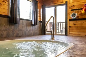 A wooden cabin interior with a hot tub, wooden walls, and a view of a wooden deck outside. - 3 Bedroom, Sleeps 10, Close to town w Pool, Hot Tub, Sauna and Game Room! (Sevierville)