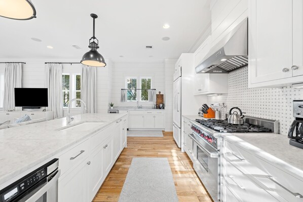 A modern kitchen with white cabinetry, a large island, a built-in oven, and a gas stove. - Golf Cart, Carriage House, Beautiful Interior Watercolor Home (Santa Rosa Beach)