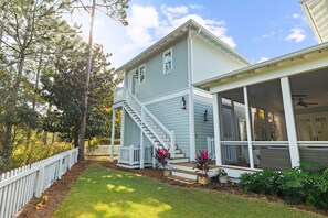 A light blue two-story house with a white porch and a covered outdoor seating area. - Golf Cart, Carriage House, Beautiful Interior Watercolor Home (Santa Rosa Beach)