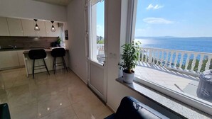 Uma cozinha moderna com área de refeições, uma varanda com vista para o mar e um vaso de plantas.