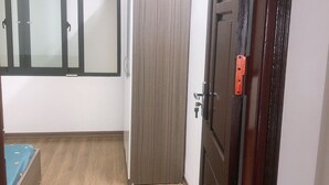 A room with a wooden floor, a bed with a blue bedspread, a wardrobe, and a door with a red handle. - Selene Home (Hanoi)