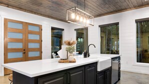 A modern kitchen with a large island, dark cabinets, white countertops, and a wooden ceiling. - Fore Sight Golf Simulator, Games, Play-Set, Pets, Tee It Up (Broken Bow)