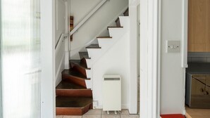 Un escalier menant à une cuisine aux murs blancs et aux marches en bois.