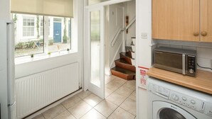 Une cuisine équipée d’un four à micro-ondes, d’un lave-linge et de meubles de rangement en bois.