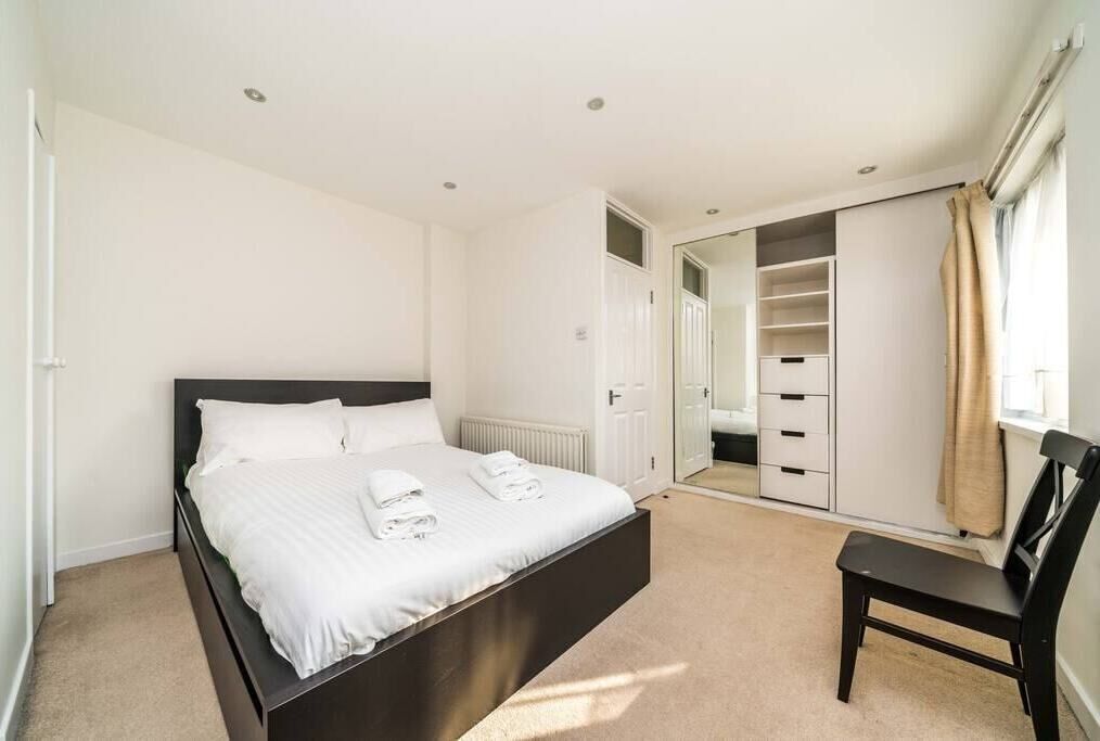 A bedroom with a bed, a chair, a wardrobe, and a mirror.