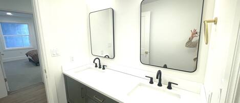 Un baño con dos lavamanos, un espejo y una ducha.