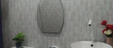 Un baño con inodoro, lavabo, ventana y espejo.