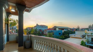Un balcon offrant une vue sur le paysage urbain au coucher du soleil.