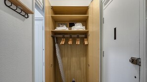 A walk-in closet with wooden shelving, a hanging rack, and a shoe rack. - Modern Bloomsbury Studio, nr Universities & Euston Station, by Blueground (London)