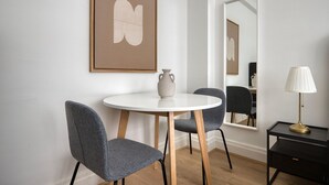 A modern dining area with a round table, two grey chairs, a vase, a lamp, and a framed artwork on the wall. - Modern Bloomsbury Studio, nr Universities & Euston Station, by Blueground (London)