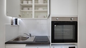 A kitchen with a sink, a dishwasher, a built-in oven, and a cabinet with dishes. - Modern Bloomsbury Studio, nr Universities & Euston Station, by Blueground (London)