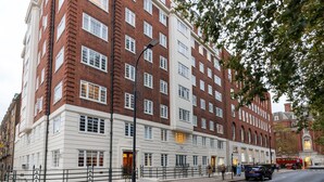 A multi-story building with a mix of brick and white facades, featuring large windows and a prominent entrance. - Modern Bloomsbury Studio, nr Universities & Euston Station, by Blueground (London)