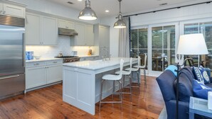 A modern kitchen with white cabinetry, stainless steel appliances, and a central island with bar stools. - Charming Southern Cottage near Tennis & Golf (Bluffton)