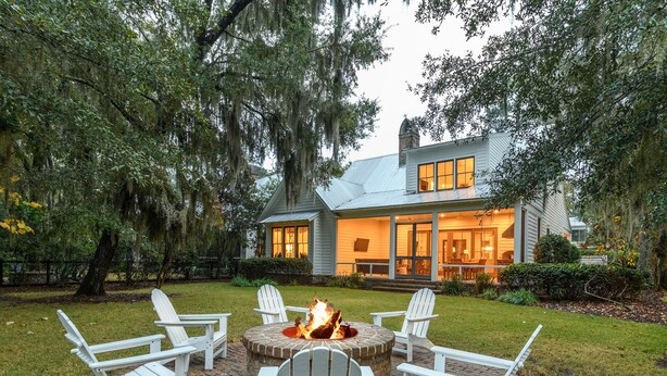 A house with a fire pit surrounded by Adirondack chairs in the backyard. - Charming Southern Cottage near Tennis & Golf (Bluffton)