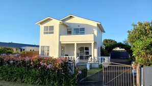 Un immeuble résidentiel à deux étages doté d’un balcon, d’un porche et d’une allée d’accès fermée par un portail.