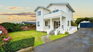 Une maison à deux étages avec un porche à l’avant, une allée et une pelouse bien entretenue.