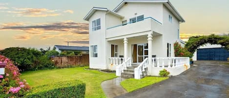 A two-story house with a front porch, a driveway, and a well-maintained lawn.