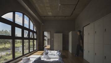 A spacious room with large windows, a sofa, and a row of lockers.