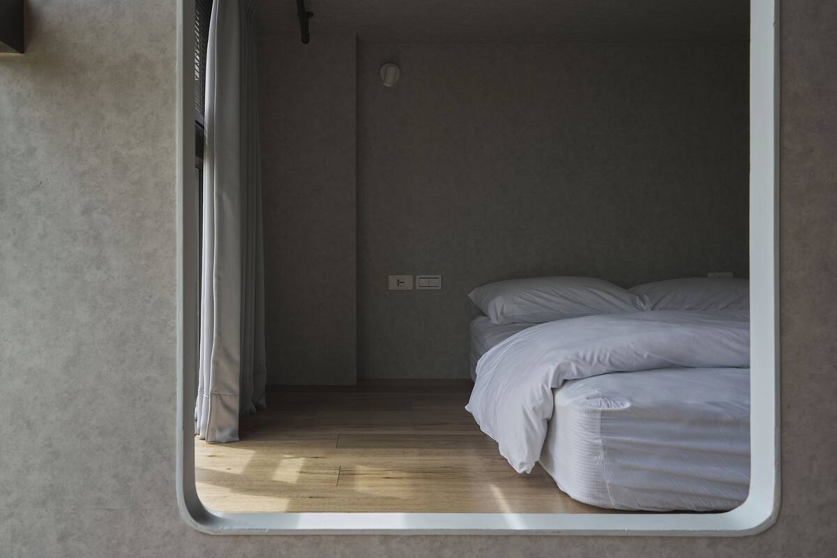 A bedroom with a bed, a window, and a door.